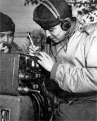 The cousins Pfc. Preston Toledo (on the left) and Pfc. Frank Toledo (both Navajo) use the Navajo language to relay orders over a field radio during a World War II Marine Corps artillery operation in the South Pacific.