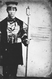 A young Iowan Wide Awake in full uniform demonstrates for the 1860 Republican candidates Abraham Lincoln (for president), Hannibal Hamlin (for vice president), and Samuel R. Curtis (for congressman). His stern expression reflects the dire, militaristic seriousness that often replaced exuberant hoopla in the Wide Awake ranks. Reprinted from “‘The Prairies A-Blaze’: Iowa Wide-Awakes Carry Torches for Lincoln,” Iowa Heritage Illustrated, 77 (Spring 1996). Courtesy Floyd and Marion Rinhart Collection, The Ohio State University Libraries.