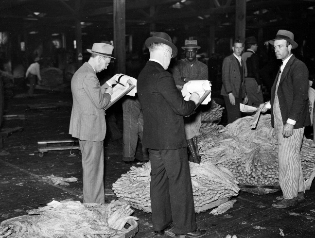 “Bookmen for the warehouse follow the sale and check the prices of tobacco after the auction. Durham, North Carolina, November 1939”